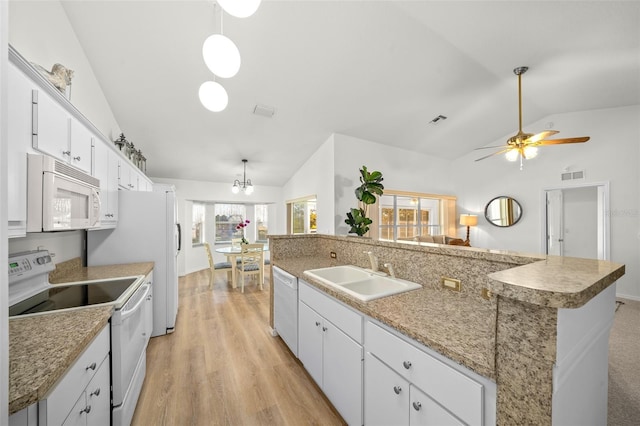 kitchen featuring vaulted ceiling, a kitchen island with sink, white appliances, and plenty of natural light