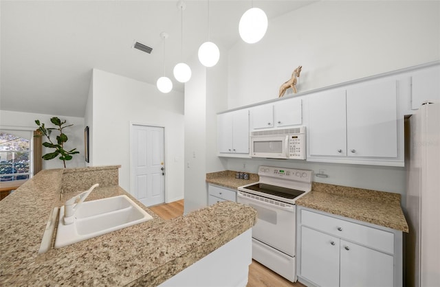 kitchen featuring white appliances, sink, hanging light fixtures, white cabinetry, and light hardwood / wood-style flooring