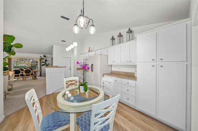 dining room featuring an inviting chandelier, light wood-type flooring, and vaulted ceiling