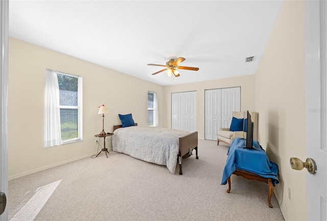 carpeted bedroom with ceiling fan and multiple closets