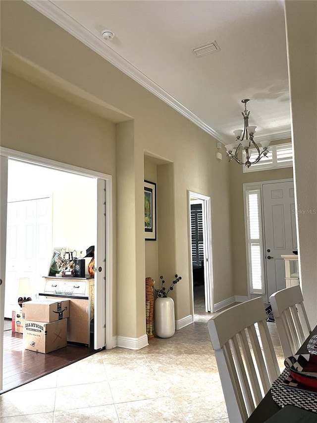 entrance foyer featuring ornamental molding, a notable chandelier, and light tile patterned floors