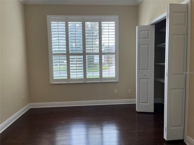 empty room featuring ornamental molding and dark wood-type flooring