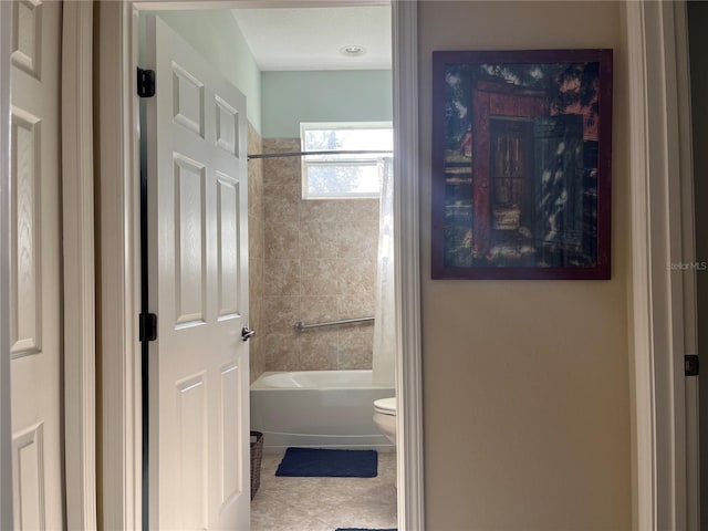 bathroom with toilet, tiled shower / bath, and tile patterned floors