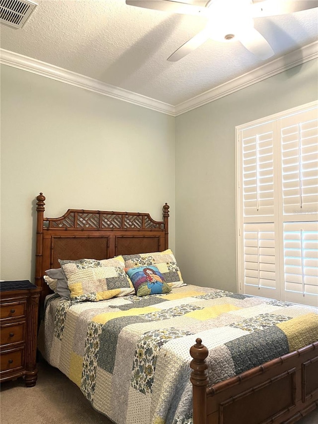 bedroom featuring ceiling fan, a textured ceiling, carpet floors, and ornamental molding