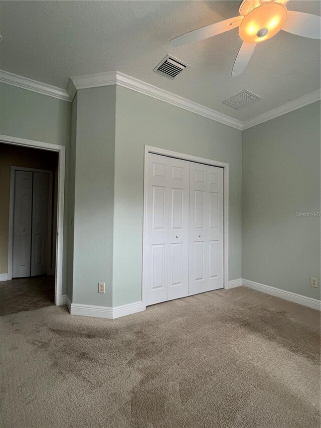 unfurnished bedroom featuring a closet, crown molding, carpet flooring, a textured ceiling, and ceiling fan