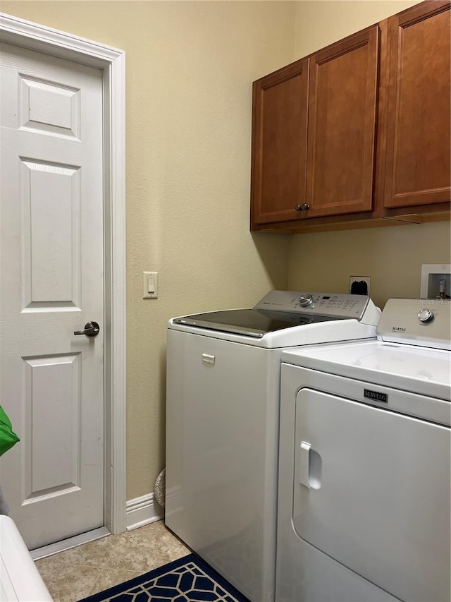 washroom featuring cabinets, light tile patterned flooring, and washing machine and clothes dryer