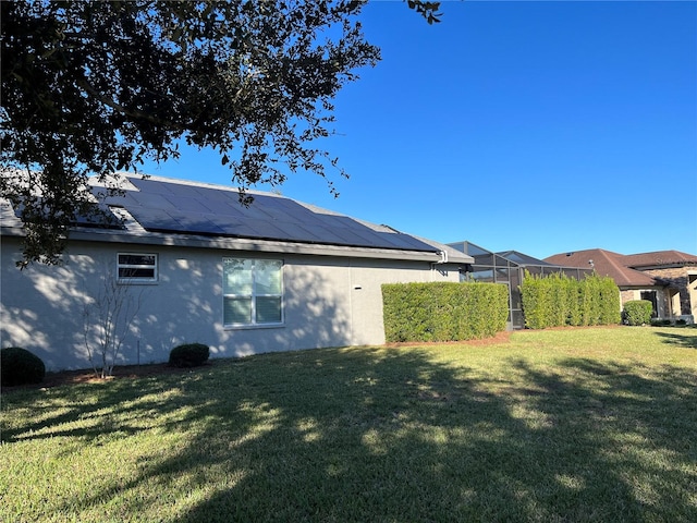 view of side of property featuring solar panels and a lawn