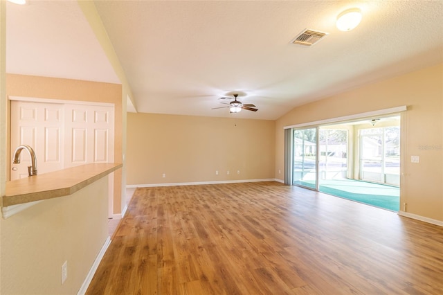 unfurnished living room featuring wood-type flooring, ceiling fan, lofted ceiling, and sink