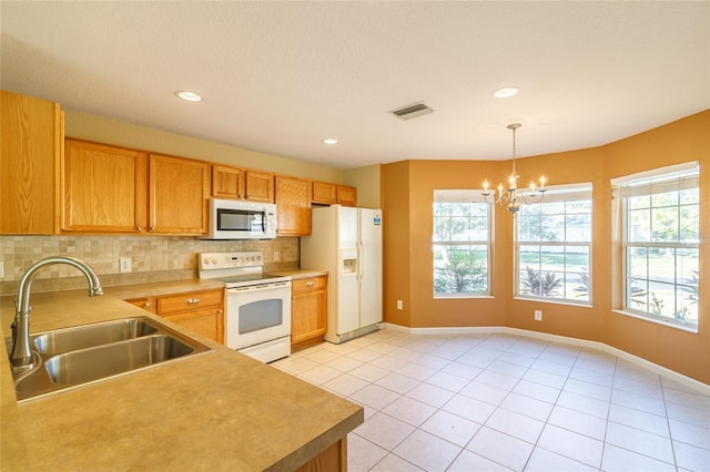 kitchen featuring tasteful backsplash, hanging light fixtures, an inviting chandelier, sink, and white appliances