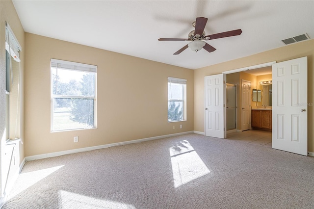 unfurnished bedroom with connected bathroom, light carpet, and ceiling fan