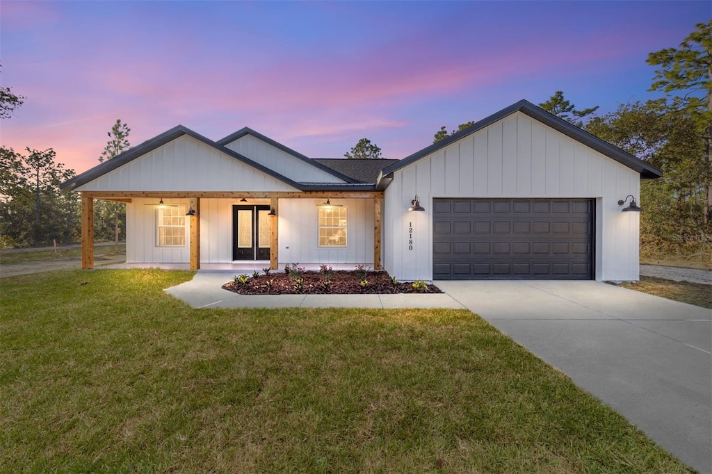 modern farmhouse style home featuring covered porch, a yard, and a garage