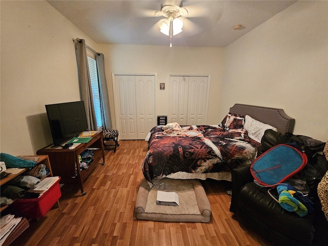 bedroom with ceiling fan, hardwood / wood-style flooring, and multiple closets