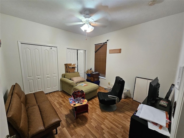 interior space with ceiling fan, a textured ceiling, and hardwood / wood-style floors