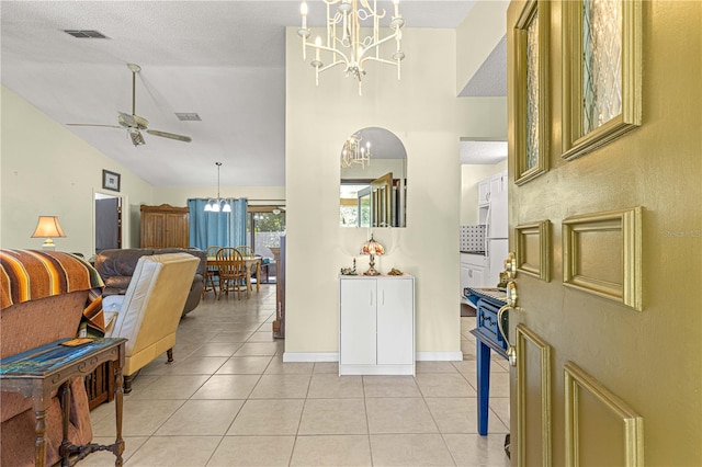 interior space with high vaulted ceiling, ceiling fan with notable chandelier, and light tile patterned floors