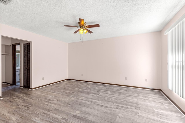 unfurnished room with a textured ceiling, ceiling fan, and light wood-type flooring