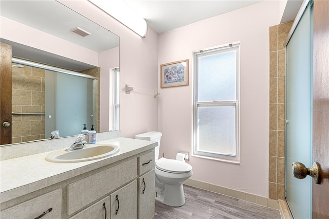 bathroom featuring vanity, hardwood / wood-style floors, a shower with door, and toilet