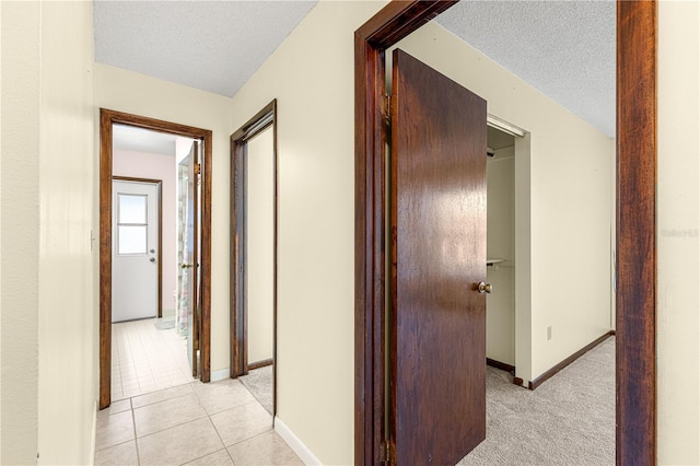 corridor with light tile patterned floors and a textured ceiling