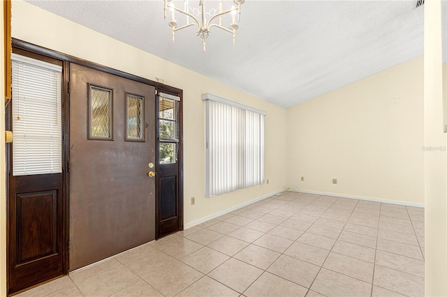 tiled foyer entrance with vaulted ceiling, a textured ceiling, and a notable chandelier