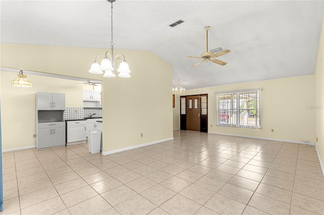 unfurnished living room featuring vaulted ceiling, ceiling fan with notable chandelier, and light tile patterned floors