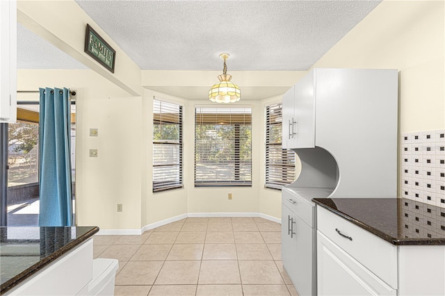 kitchen featuring pendant lighting, white cabinetry, dark stone countertops, and light tile patterned flooring