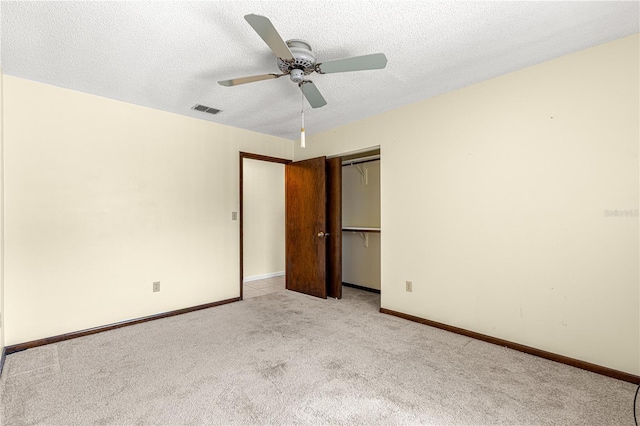 unfurnished bedroom featuring ceiling fan, light carpet, a closet, and a textured ceiling