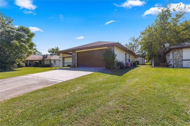 view of front of property with a garage, cooling unit, and a front lawn