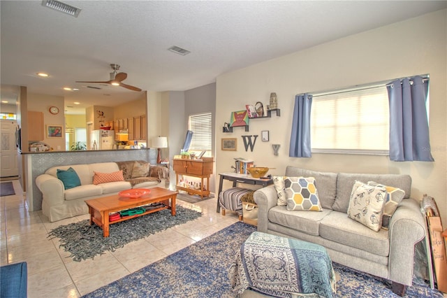 living room with a textured ceiling, plenty of natural light, ceiling fan, and light tile patterned flooring