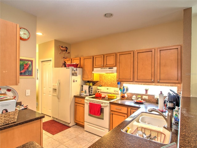 kitchen featuring dark stone counters, white appliances, sink, and light tile patterned flooring