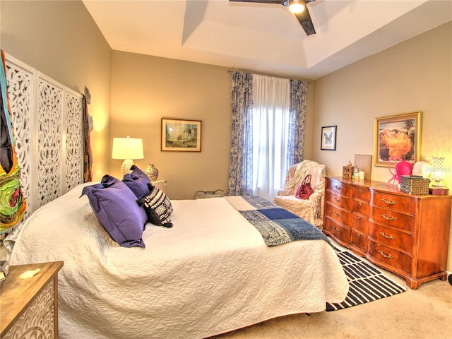 bedroom featuring a tray ceiling, carpet, and ceiling fan