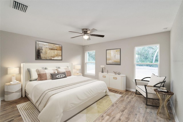 bedroom with light hardwood / wood-style floors, multiple windows, and ceiling fan