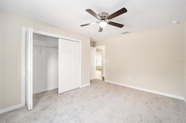 unfurnished bedroom with light colored carpet, a closet, and ceiling fan