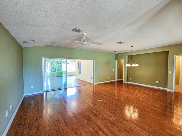 empty room featuring a textured ceiling, vaulted ceiling, hardwood / wood-style flooring, and ceiling fan with notable chandelier