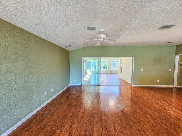 empty room with a textured ceiling, ceiling fan, wood-type flooring, and vaulted ceiling