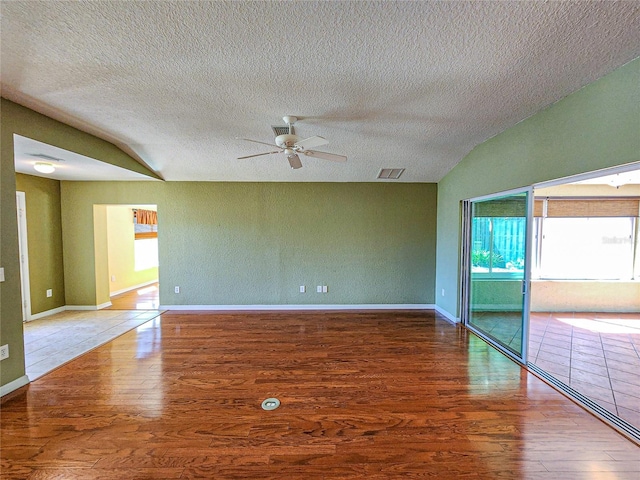 empty room featuring ceiling fan, a textured ceiling, vaulted ceiling, and hardwood / wood-style floors