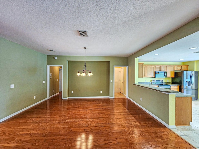 unfurnished living room with a notable chandelier, a textured ceiling, and dark hardwood / wood-style floors