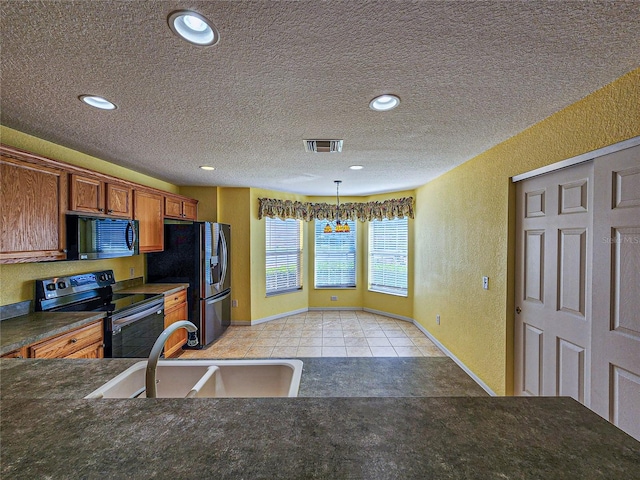 kitchen with a textured ceiling, black appliances, sink, and pendant lighting