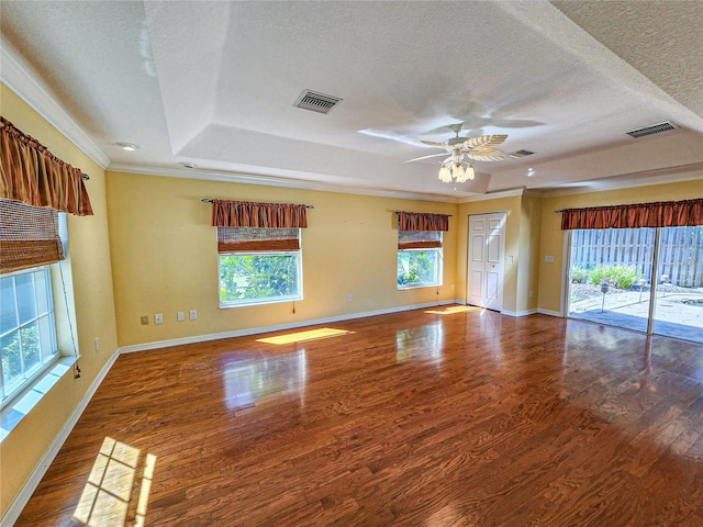 unfurnished living room with a raised ceiling, ceiling fan, a textured ceiling, wood-type flooring, and ornamental molding