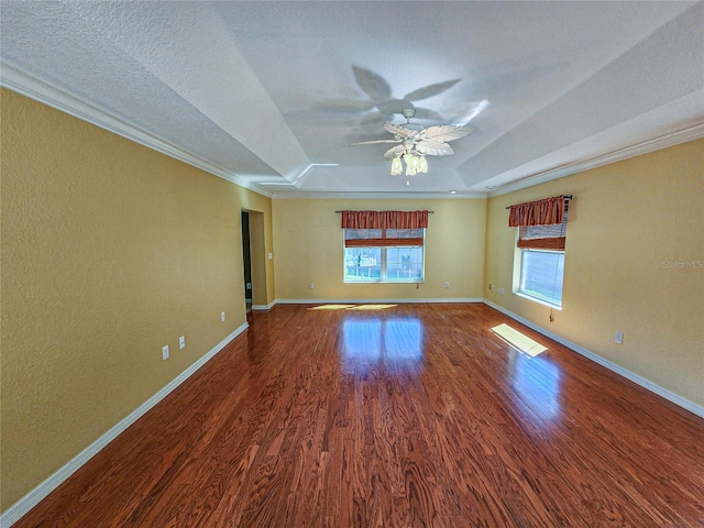 empty room with ornamental molding, hardwood / wood-style floors, a tray ceiling, and ceiling fan