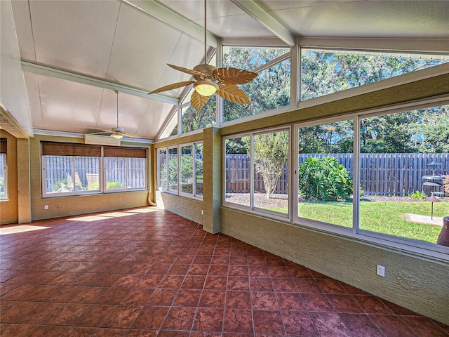 unfurnished sunroom featuring ceiling fan, a wealth of natural light, and vaulted ceiling with beams