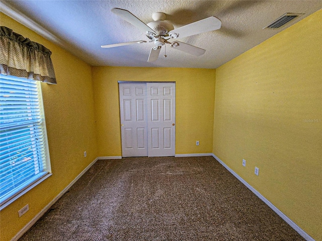 unfurnished bedroom with a closet, ceiling fan, a textured ceiling, and carpet floors