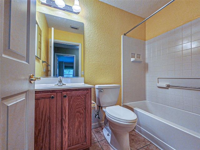 full bathroom with a textured ceiling, toilet, tiled shower / bath, vanity, and tile patterned flooring