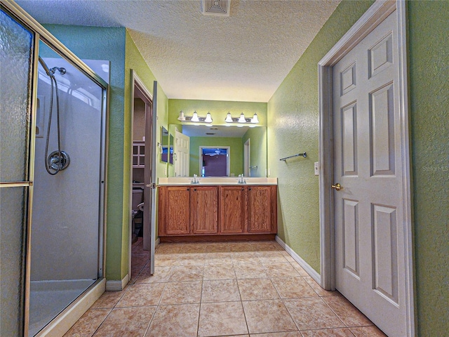 bathroom with vanity, tile patterned flooring, a textured ceiling, and walk in shower