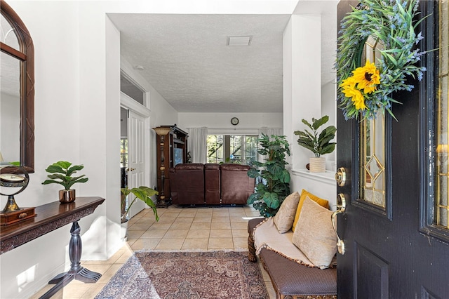 entryway with light tile patterned flooring, a textured ceiling, and visible vents