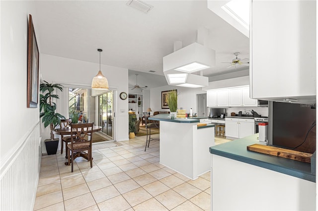 kitchen featuring white cabinets, hanging light fixtures, light tile patterned floors, a kitchen bar, and kitchen peninsula