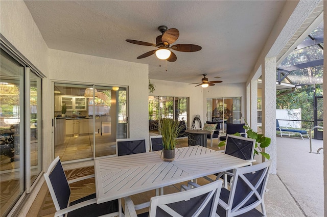 sunroom / solarium with ceiling fan, carpet floors, a textured wall, and a textured ceiling