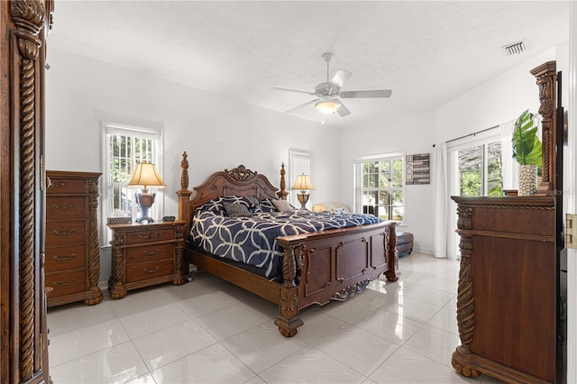 tiled bedroom with multiple windows, ceiling fan, and a textured ceiling