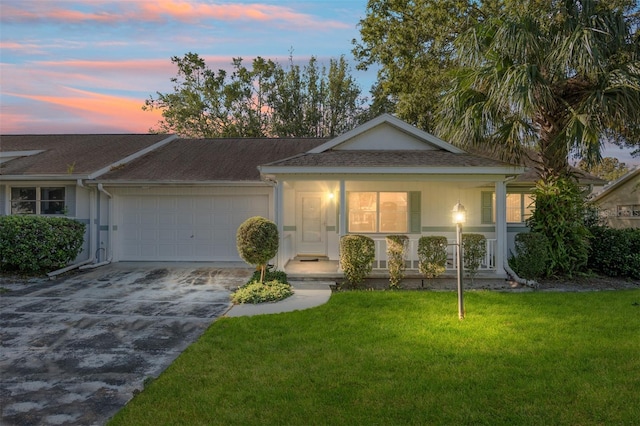 ranch-style house featuring a yard, covered porch, and a garage