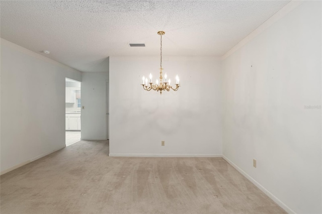 spare room featuring a textured ceiling, light colored carpet, and an inviting chandelier