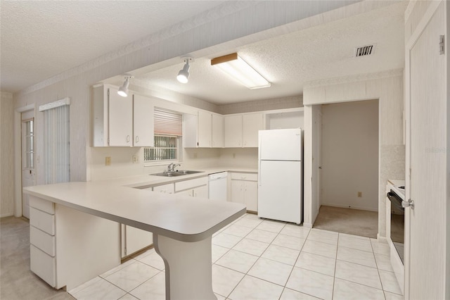 kitchen with kitchen peninsula, light tile patterned flooring, white cabinets, a textured ceiling, and white appliances