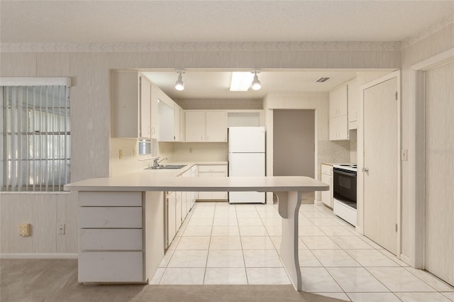 kitchen with a textured ceiling, white cabinetry, light tile patterned flooring, sink, and white appliances